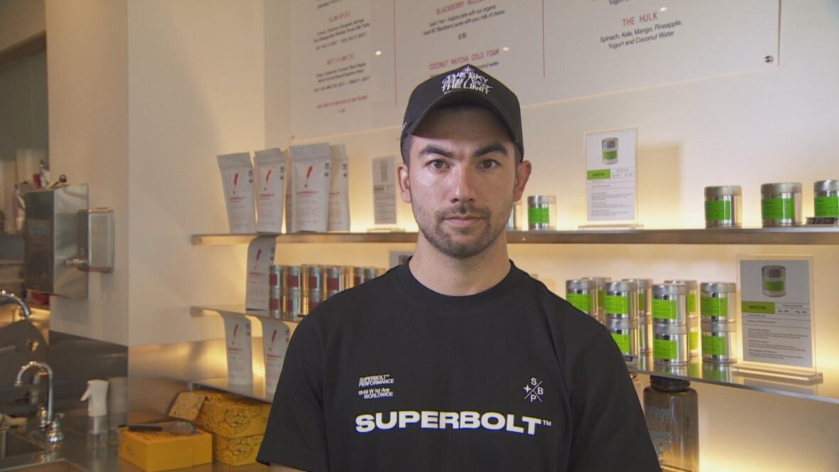 A man with a black shirt poses in front of a cafe display.