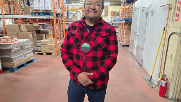Marten Falls First Nation Chief Bruce Achneepineskum poses for a photo at the Cav-Tal Foods building in Thunder Bay. Marten Falls has acquired the company, as well as Bay Meats. A man smiles and poses for a photo in a food distribution warehouse.