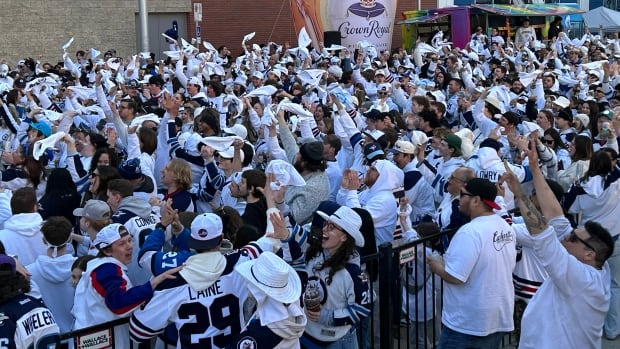 A group of people dressed in white cheer.