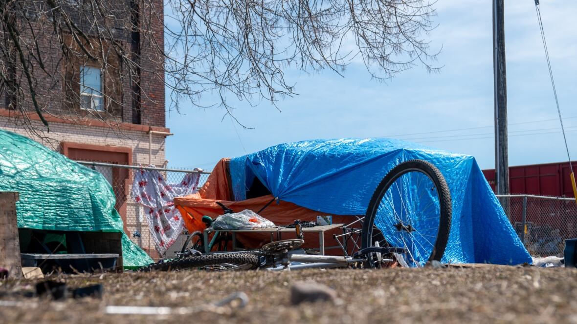 Tents are seen covered successful  tarps outside. A bicycle is besides  seen connected  the ground.