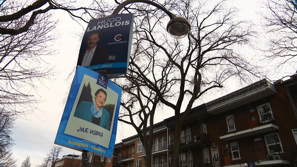 Two predetermination  signs, 1  for the Conservative, 1  for the Bloc Québécois, are seen connected  a streetlamp.