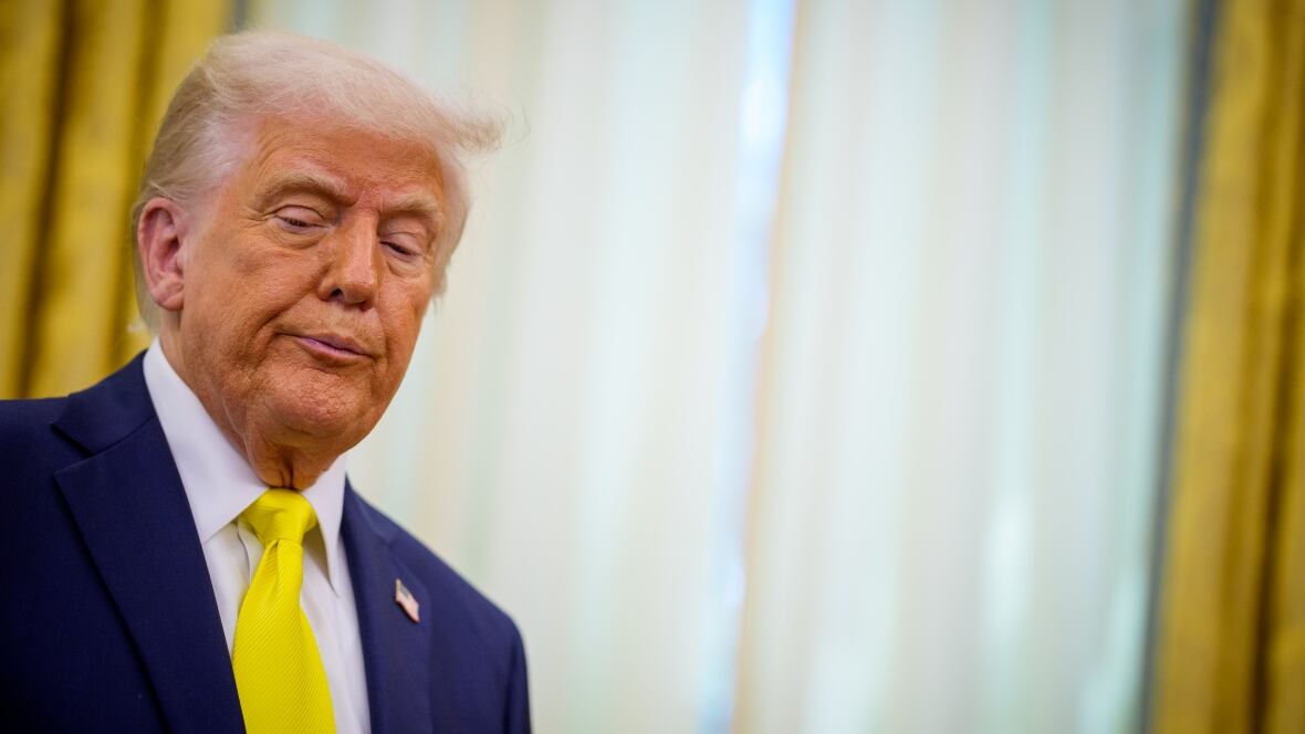 A antheral   successful  a navy bluish  suit   and yellowish  necktie  looks downward, portion    lasting  successful  beforehand   of a model   with achromatic  and yellowish  drapes.