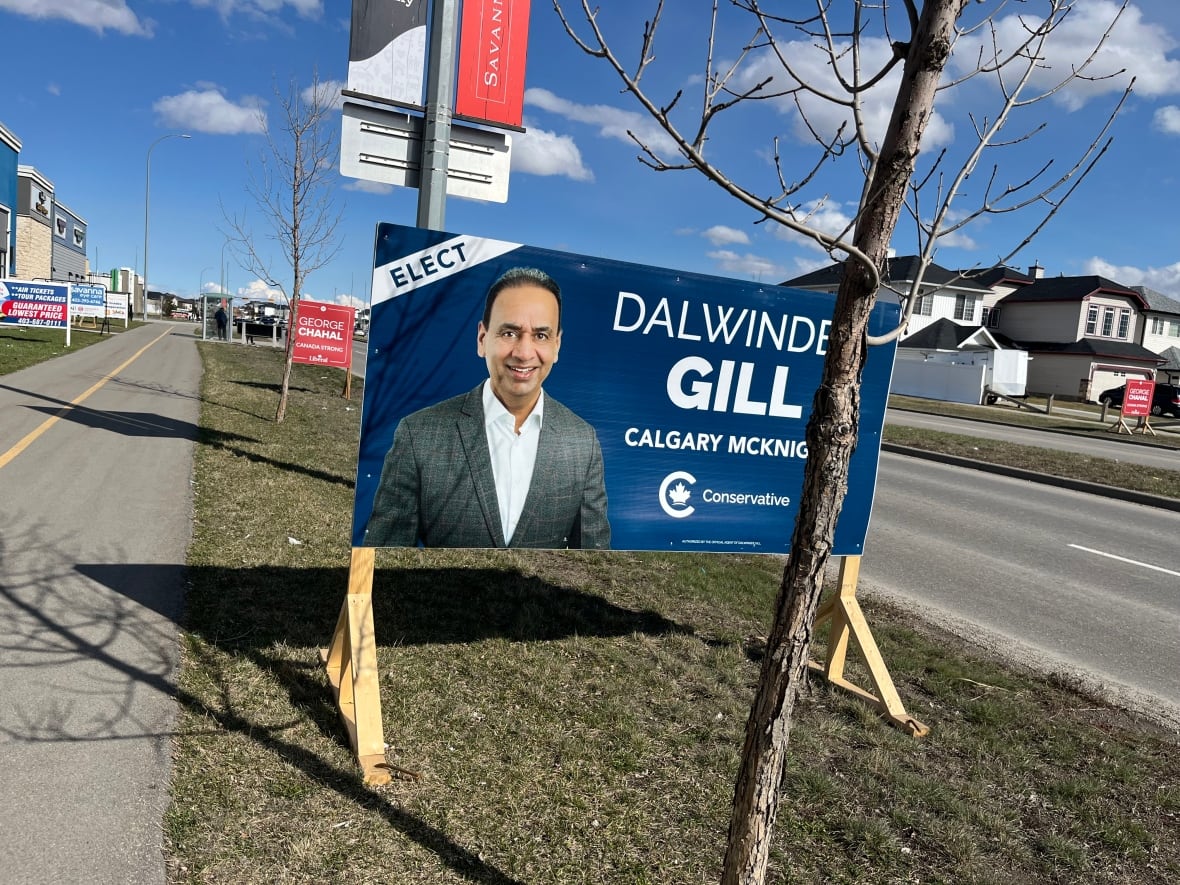 A large blue roadside sign in front of a smaller red one
