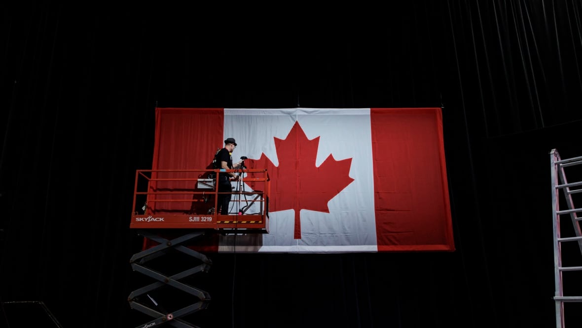 A idiosyncratic   connected  a cherry picker successful  beforehand   of a ample  Canadian flag.