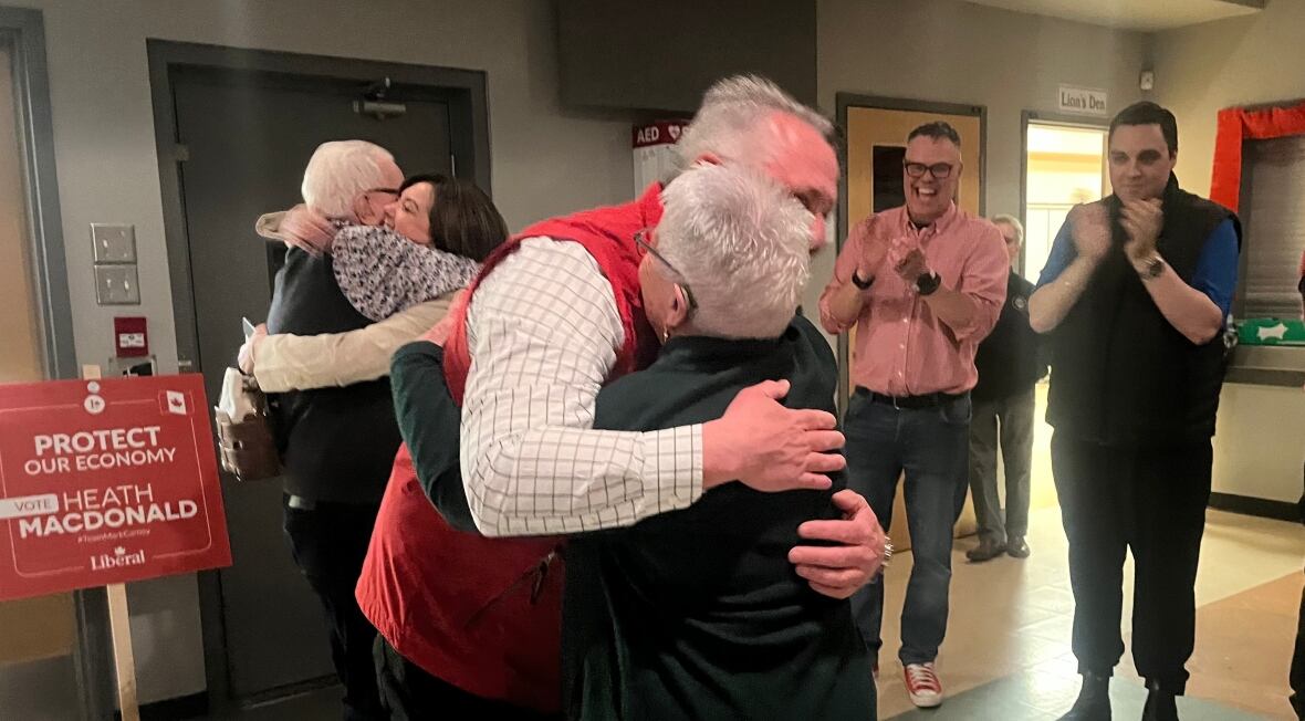 Man successful  reddish  vest hugs an older woman. 