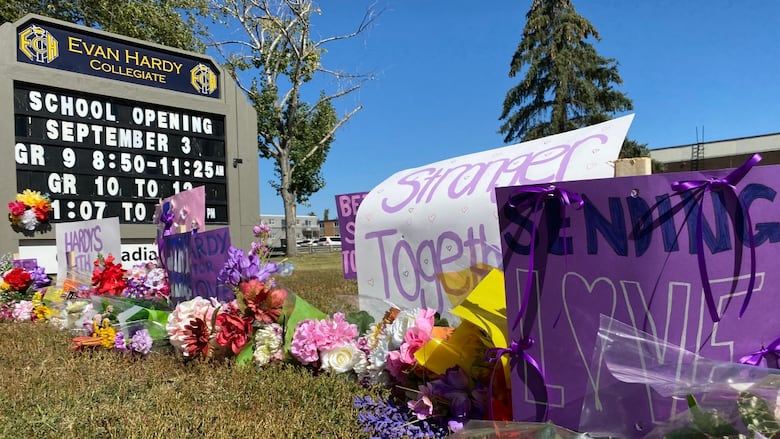 Signs and flowers sit outside a school.