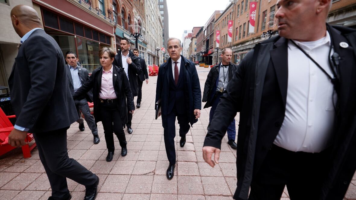 A antheral   successful  a suit   walks down   a thoroughfare  surrounded by plainclothes information    officers.