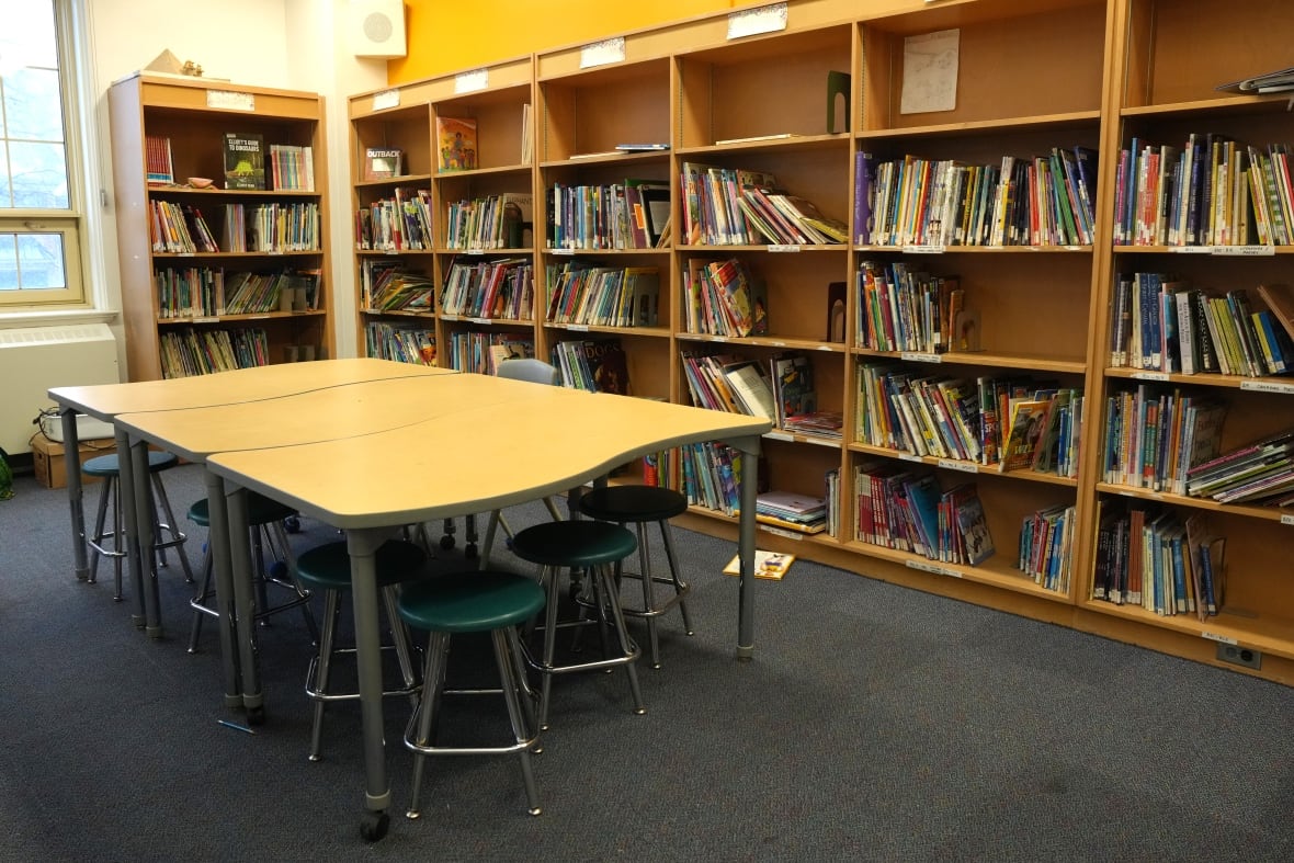 Se ven libros en los gabinetes de la habitación con una mesa.