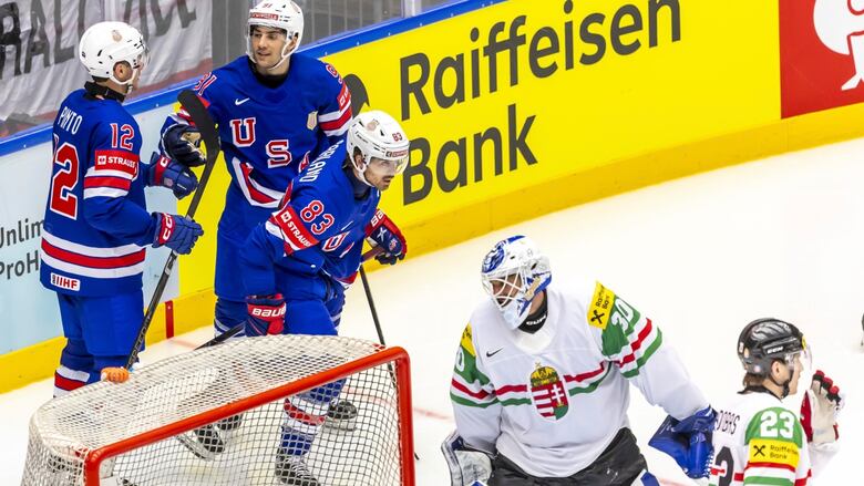 Three antheral  crystal  hockey players representing the United States interaction   gloves successful  solemnisation  down  the opposing team's nett  and goaltender.
