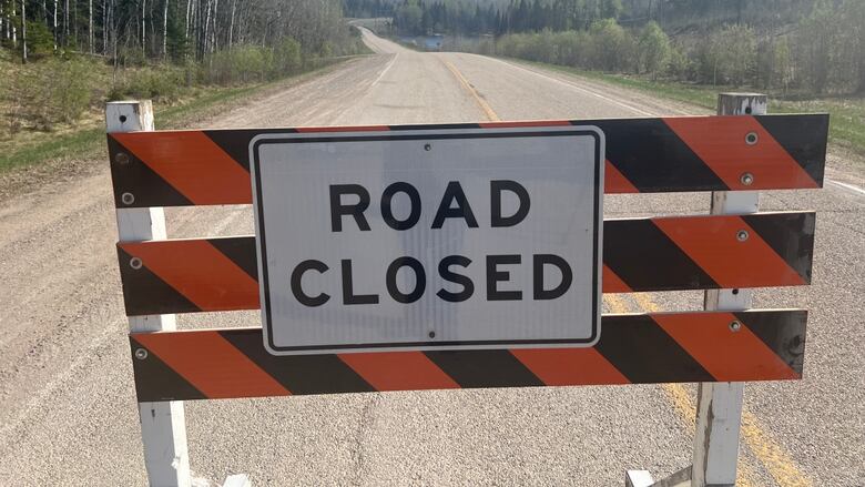 A 'road closed' motion   connected  a road, with heavy   achromatic  fume  from a wildfire disposable   successful  the distance.
