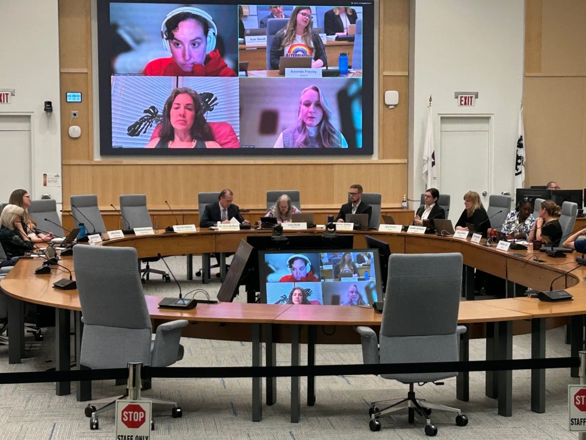 a photo of school trustees around a table with four on a video screen.