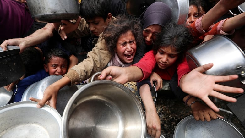 People cry and scream while holding out empty pots and dishes
