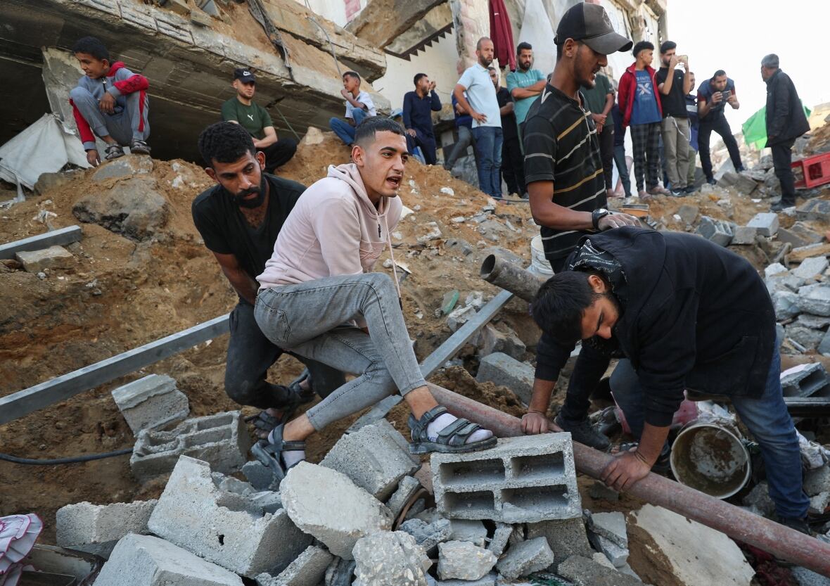 People pull through rubble in a crater left by a strike