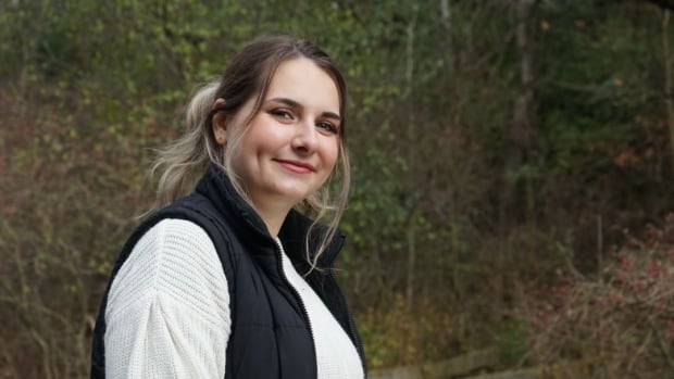 A woman smiles at the camera while out in nature