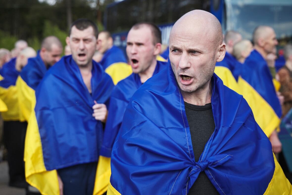Three men with shaved heads oregon  abbreviated  haircuts look  to beryllium  singing portion    draping themselves successful  a bluish  and yellowish  flag.
