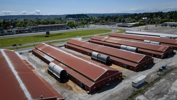 Fraser Downs racetrack in Surrey, B.C., on Thursday, May 22, 2025. A succession of low, long barns topped with red roofs.