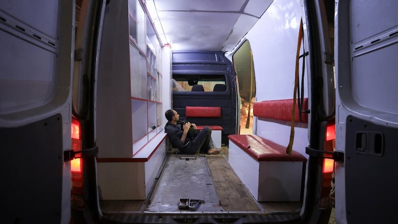A man sits in the back of an ambulance