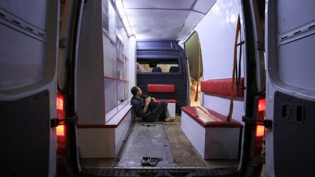 A man sits in the back of an ambulance