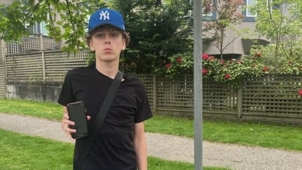 A white teenager wearing a blue hat and shorts poses for a picture.