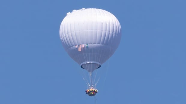 A white air balloon is seen in the sky.