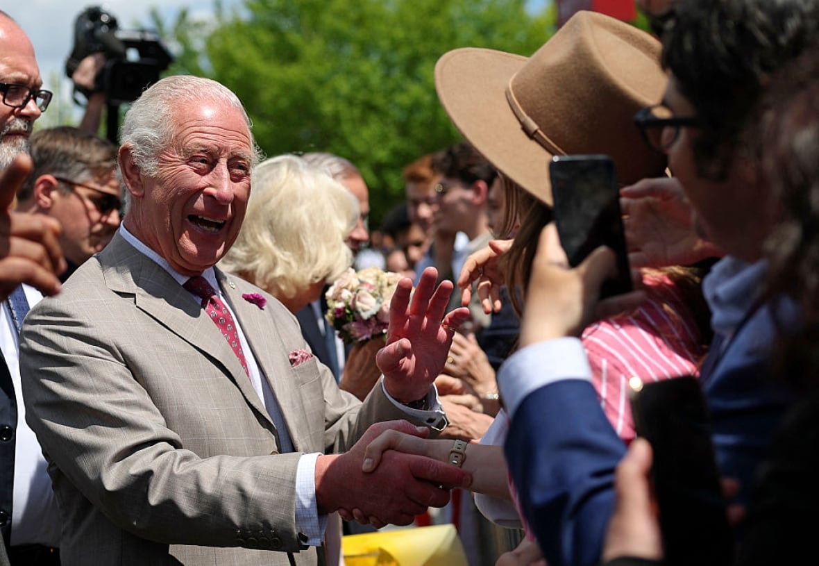 A person laughs as they shake hands with a person in a crowd.