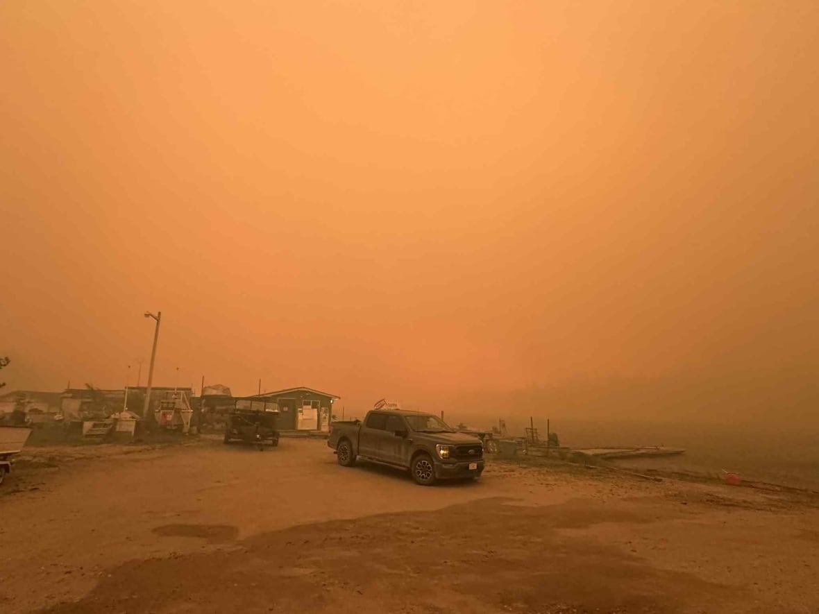 Orange smokey sky. Trucks in the foreground.