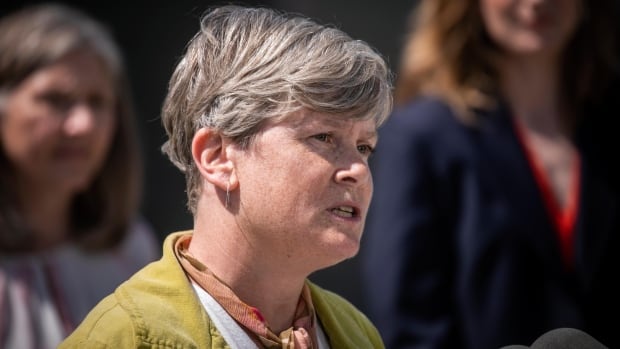 A woman with short, grey-white hair speaks.