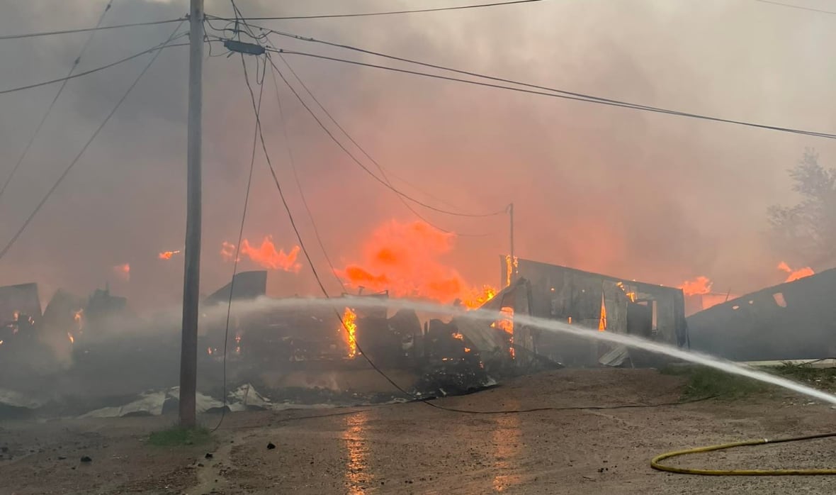 A building burns while water is sprayed on it.