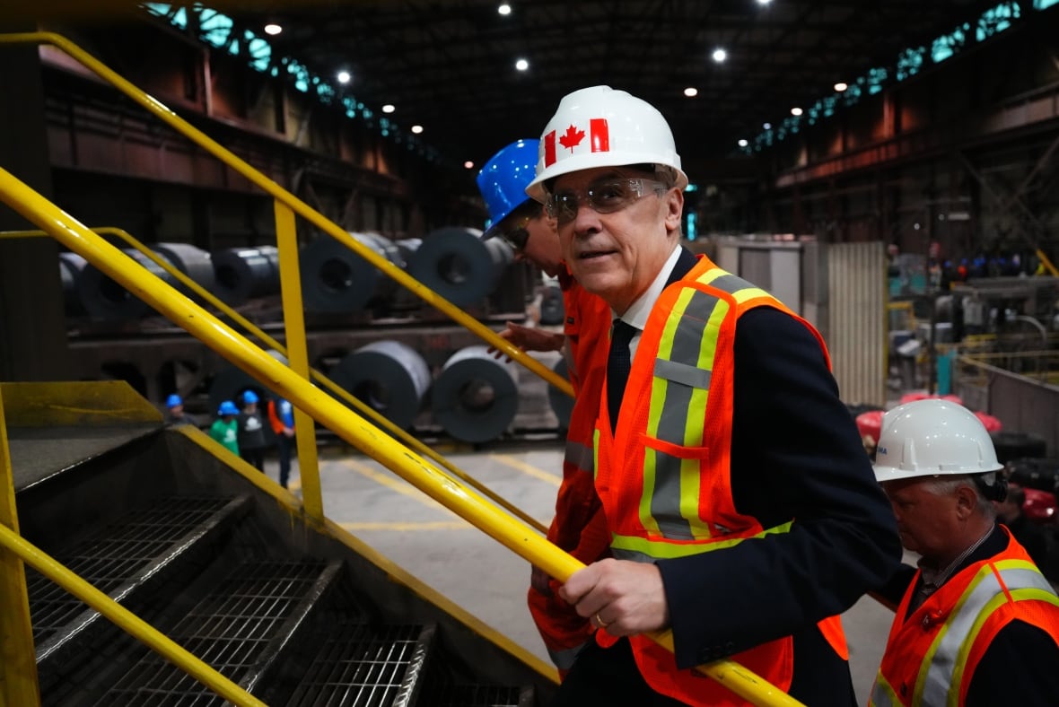 A man in a hard hat climbs the stairs in a factory.