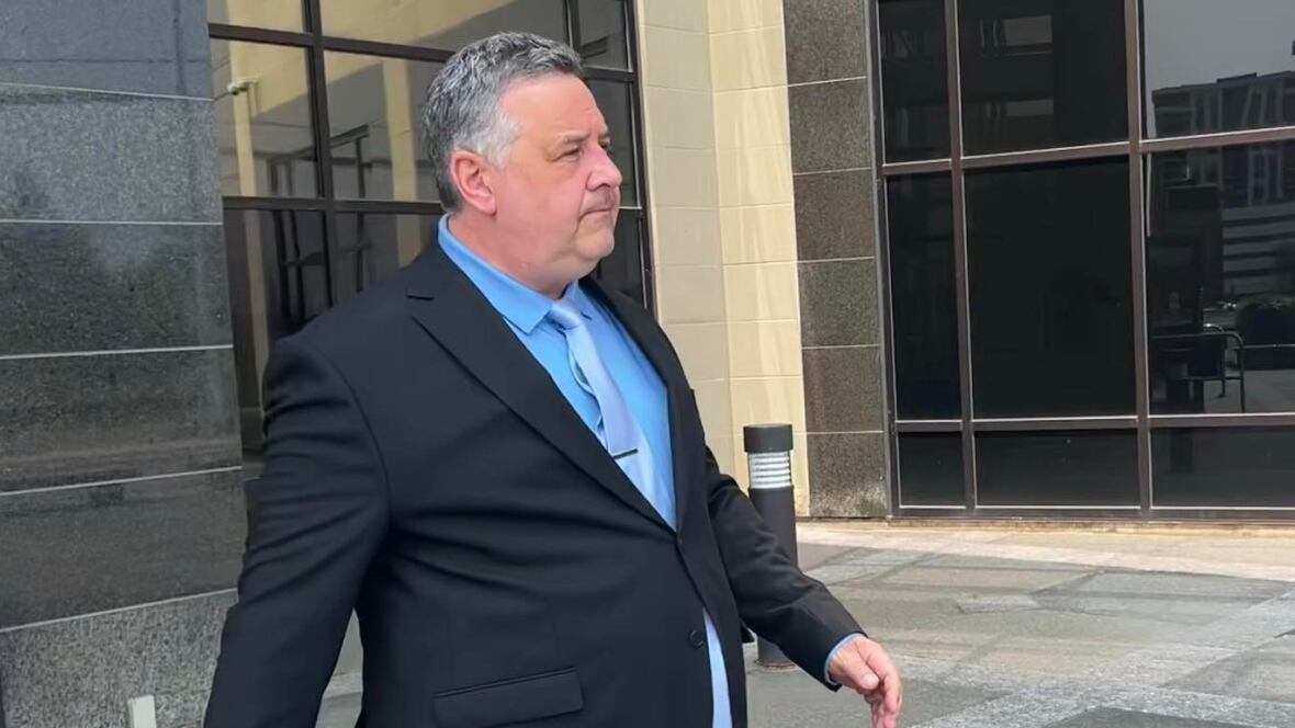 A man in a black suit walking out of the court in Moncton.
