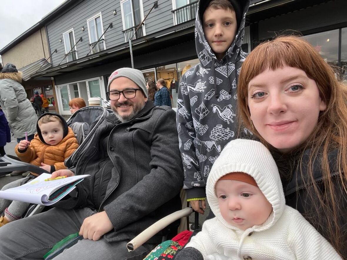 Una mujer con cabello largo y castaño se sienta con tres niños y un hombre barbudo con un tok.