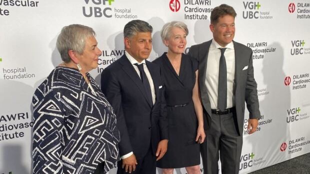 Two men and two women pose for a photograph during an event.