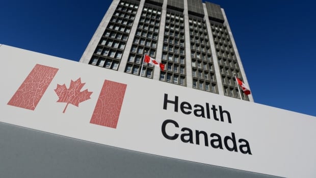 The facade of a building features the words, 'Health Canada,' and a number of Canadian flags.