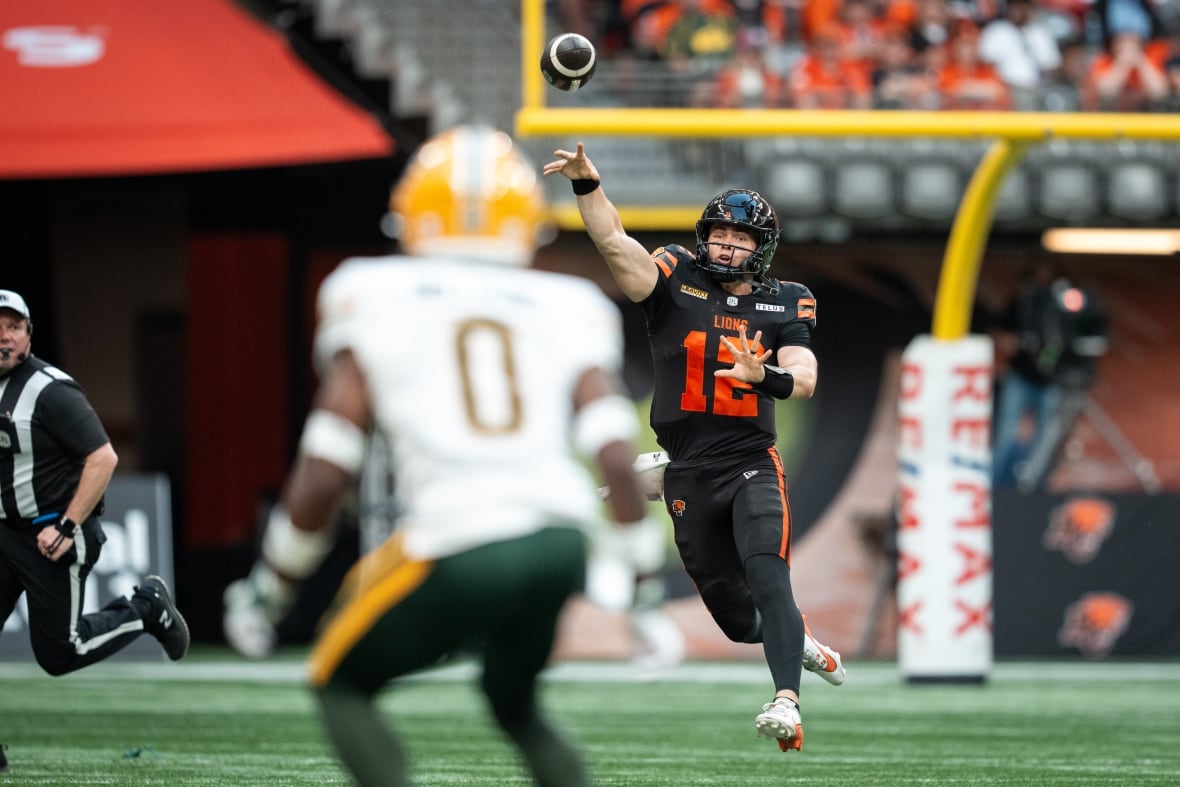 B.C. Lions quarterback Nathan Rourke (12) throws the ball as Edmonton Elks' Kobe Williams (0) watches during the first half of a CFL football game in Vancouver, on Saturday, June 7, 2025. 