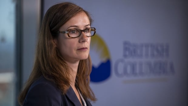 A white woman with brown hair is seen looking to her right, with a screen behind her reading'British Columbia'.