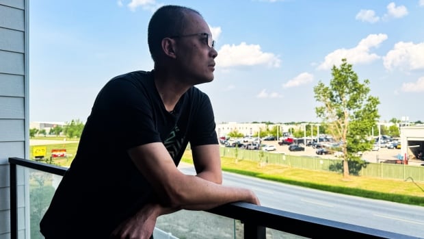 A man on a balconly looking towards the horizon