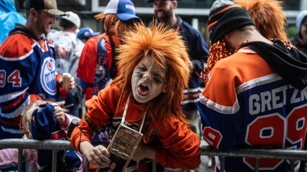 Fans cheer as they wait to watch the Florida Panthers and the Edmonton Oilers in Game 5 of the NHL Stanley Cup final in Edmonton, Saturday, June 14, 2025. A person with wild hair.