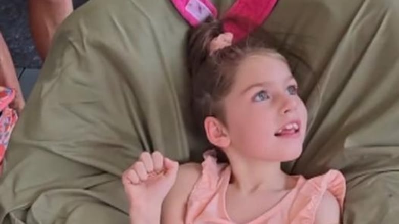 A girl in a chair wearing a peach outfit.