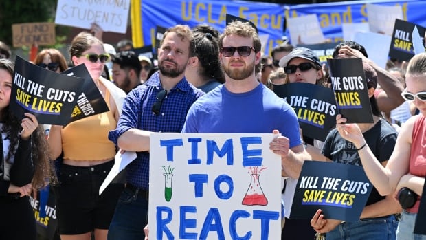 UCLA students, researchers and demonstrators rally during a "Kill the Cuts" protest against the Trump administration's funding cuts on research, health and higher education at the University of California Los Angeles (UCLA) in Los Angeles on April 8, 2025. (Photo by Robyn Beck / AFP) (Photo by ROBYN BECK/AFP via Getty Images) A group of people stand with signs protesting cuts in funding to science.
