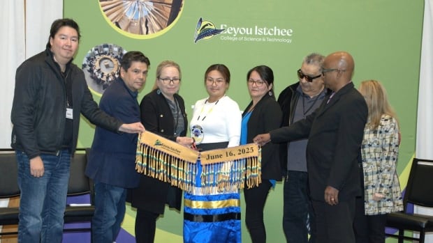 A group of people cut a moose-hide ribbon to open the Eeyou Istchee College. 