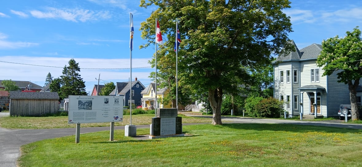 A peaceful scene with a memorial resembling a headstone and flags behind it.
