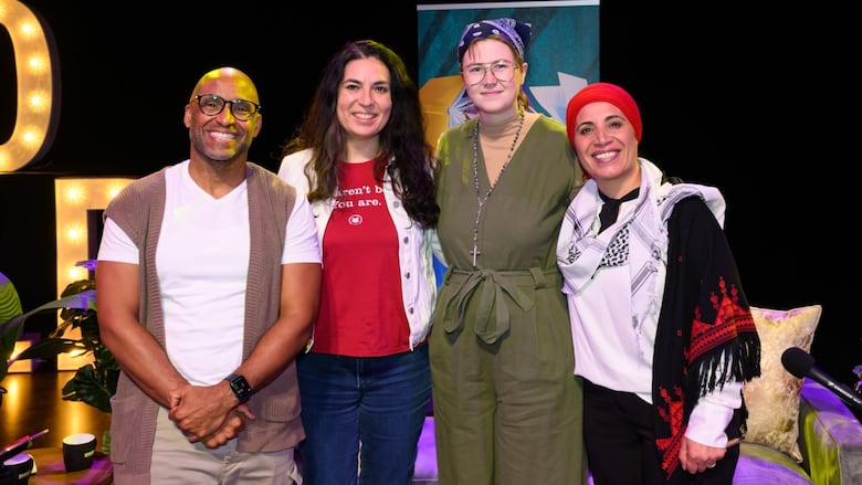 Four people stand onstage at a literary festival. A bald man with glasses, a woman with black hair wearing a red shirt, a person wearing an olive jumpsuit, glasses and a blue bandana, a woman wearing a red head covering and a keffiyeh.