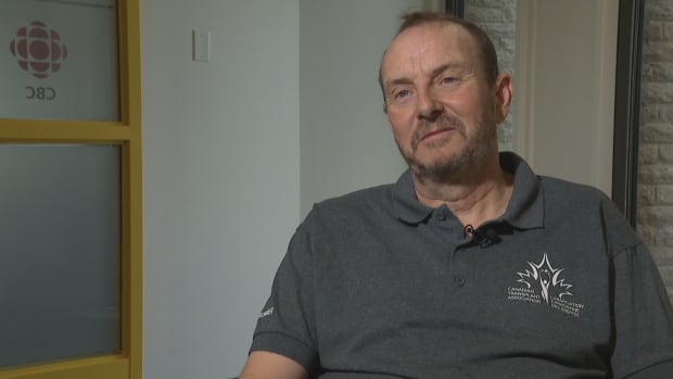 A middle-aged man sits in an office on a sunny spring day. He could use a shave.