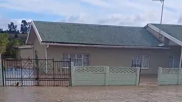 A house on a street that's filled with muddy water.