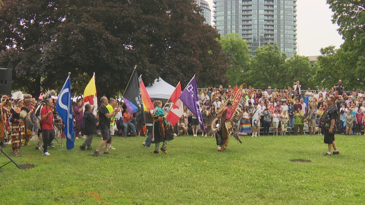 A assemblage  of hundreds watches a emblem  presumption    astatine  a powwow connected  a grassy tract   successful  Toronto successful  daytime