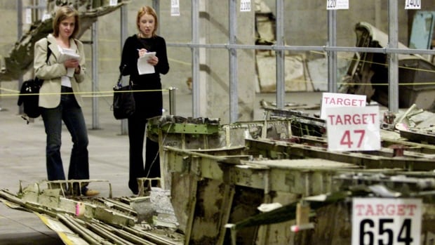 Two women look over labeled pieces of airplane wreckage in a photo from 2004.