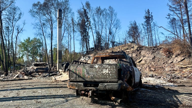 A burnt out truck surrounded by rubble.