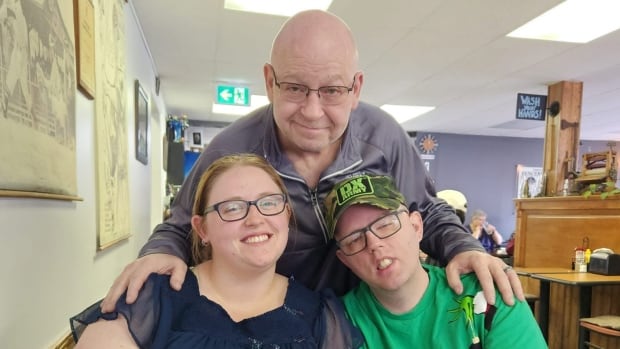 A man poses with his two adult children.