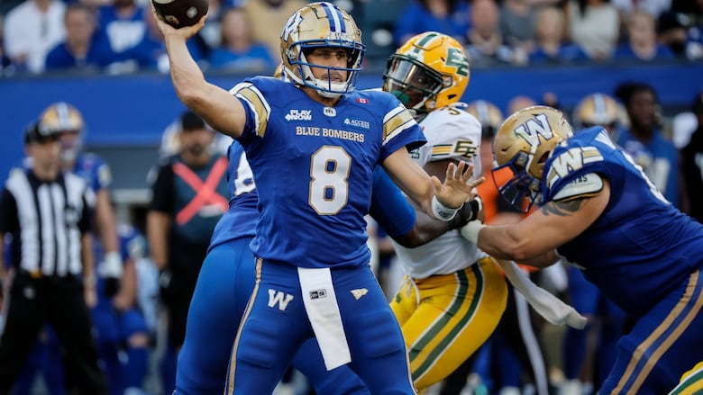 A quarterback in blue throws the ball with other players around him.