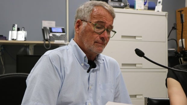 a man looks at a poiece of paper sitting in front of a microphone 